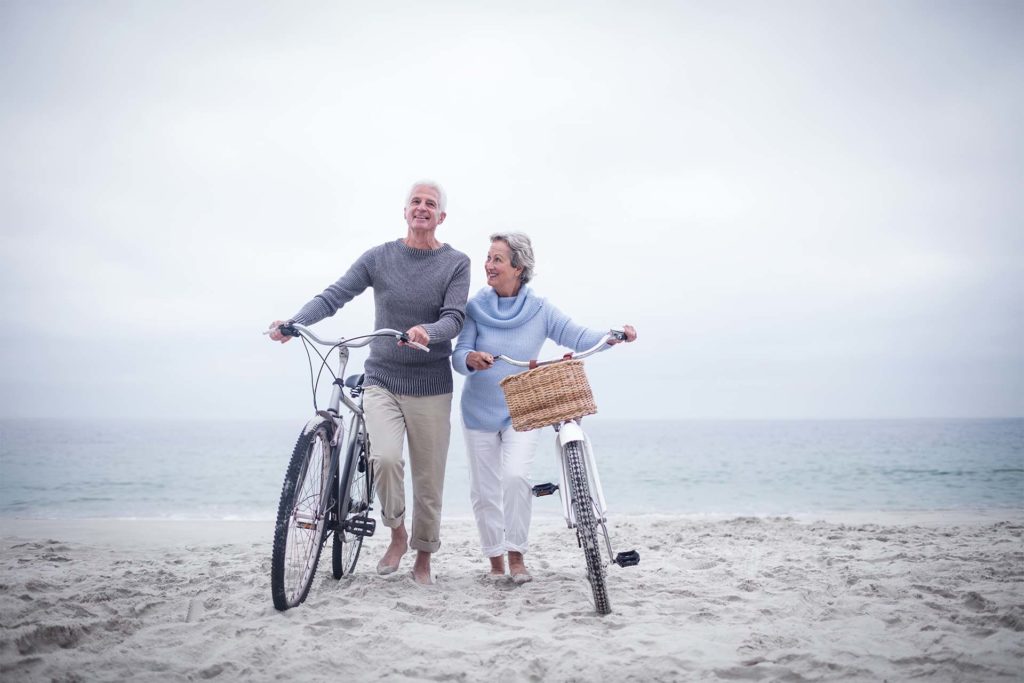Couple de personnes âgées à vélo sur la plage